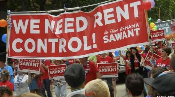 Photo of a rally for rent control in Seattle. A red banner says: 