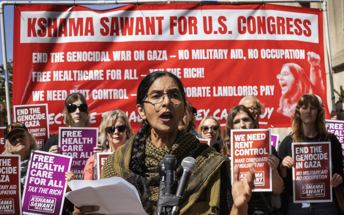 Kshama Sawant standing in front a banner announcing her run for Congress.